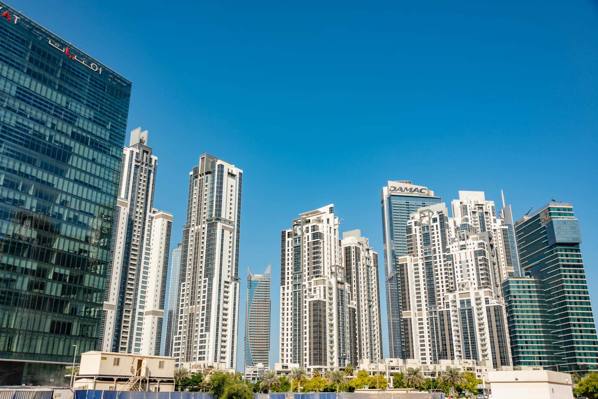 Modern skyscrapers stand tall against a clear blue sky in a vibrant cityscape, showcasing urban architecture.